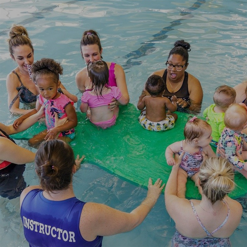 several-moms-helping-toddlers-balance-on-floatation-device-overlay