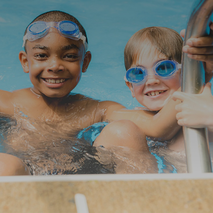 two-smiling-teenage-boys-climbing-out-of-pool-square-bg